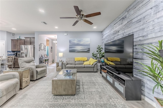 living room featuring ceiling fan and wooden walls