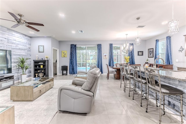 tiled living room featuring sink and ceiling fan with notable chandelier