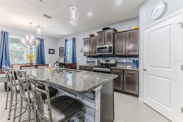 kitchen featuring stainless steel appliances, hanging light fixtures, sink, and a kitchen bar