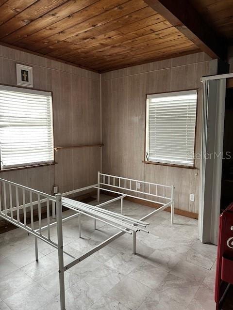 unfurnished bedroom with wooden walls, wooden ceiling, and beamed ceiling