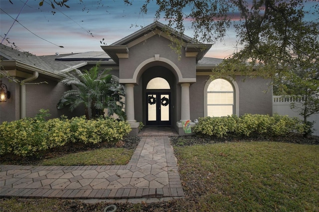 exterior entry at dusk featuring a lawn