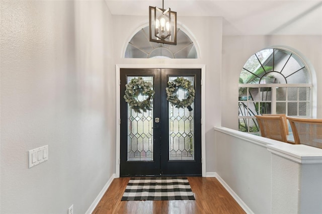 entrance foyer featuring french doors, a notable chandelier, and dark hardwood / wood-style flooring