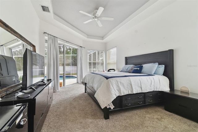 bedroom featuring ceiling fan, a tray ceiling, access to outside, and carpet flooring