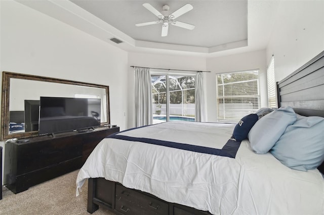 carpeted bedroom featuring ceiling fan, a tray ceiling, and access to outside