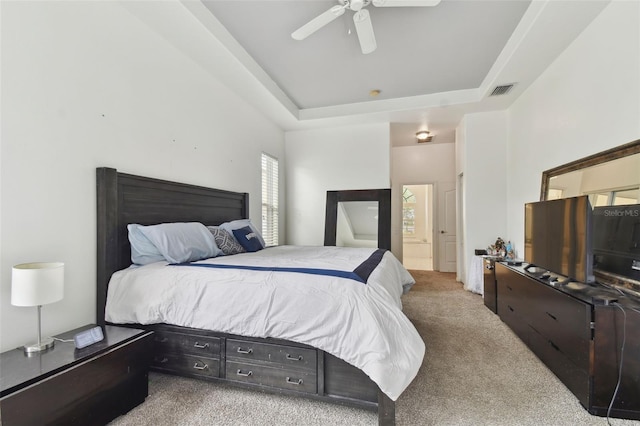 carpeted bedroom with ceiling fan and a tray ceiling