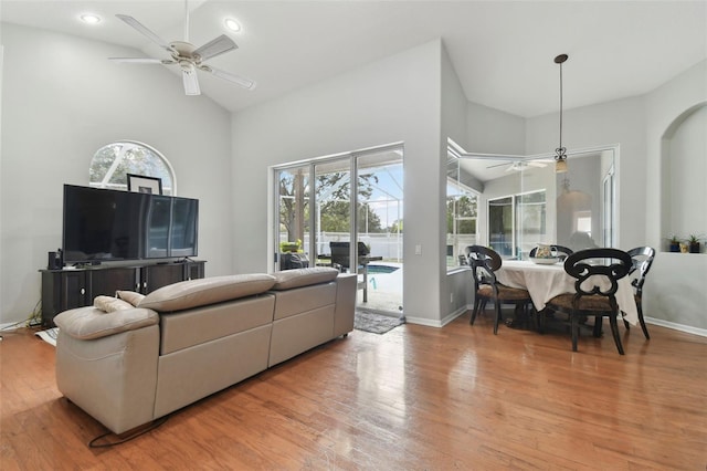 living room with ceiling fan, a high ceiling, and wood-type flooring