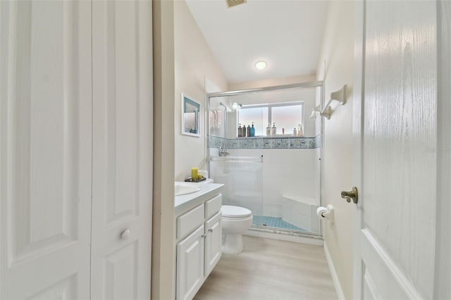 bathroom with a shower with shower door, hardwood / wood-style flooring, toilet, and vanity