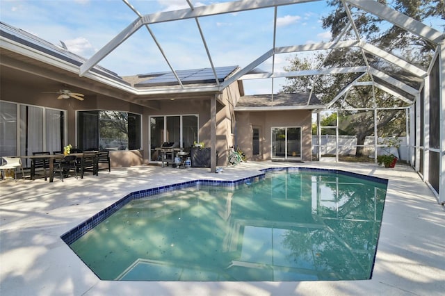 view of swimming pool with glass enclosure, ceiling fan, and a patio