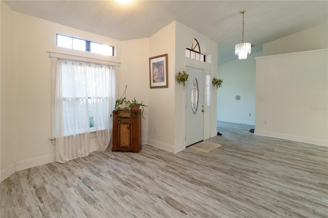 spare room featuring a textured ceiling, light hardwood / wood-style flooring, and a chandelier