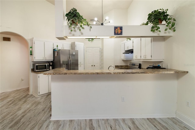 kitchen featuring light hardwood / wood-style flooring, appliances with stainless steel finishes, white cabinetry, high vaulted ceiling, and kitchen peninsula