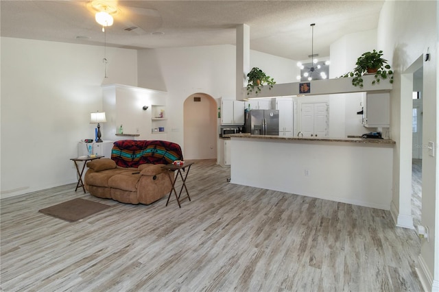 living room featuring high vaulted ceiling, a textured ceiling, and light wood-type flooring