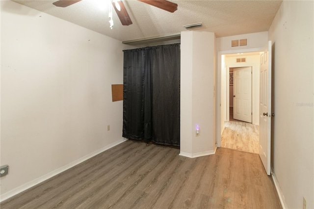 unfurnished room featuring ceiling fan, hardwood / wood-style floors, and a textured ceiling