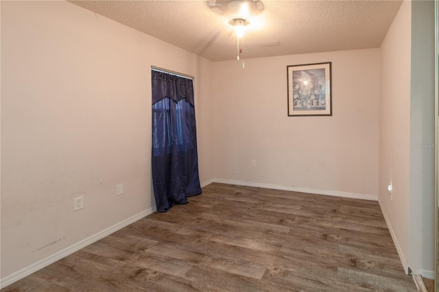 empty room with hardwood / wood-style floors and a textured ceiling