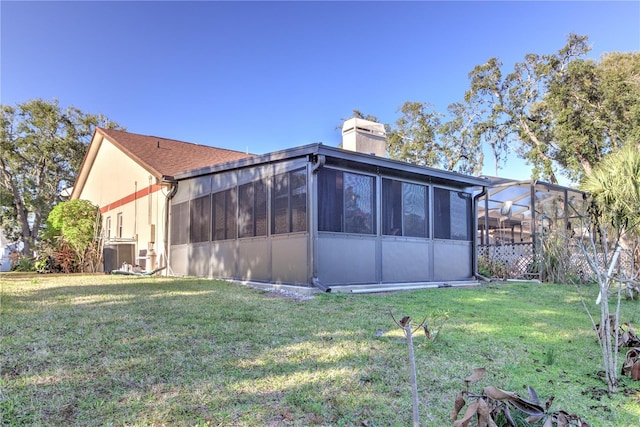 rear view of house featuring cooling unit, a lanai, and a lawn