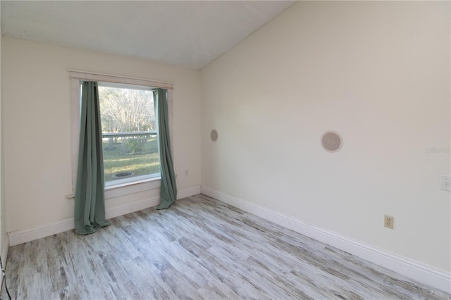 unfurnished room with lofted ceiling and light wood-type flooring