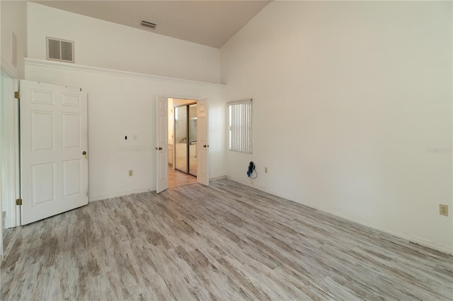 spare room with high vaulted ceiling and light hardwood / wood-style flooring