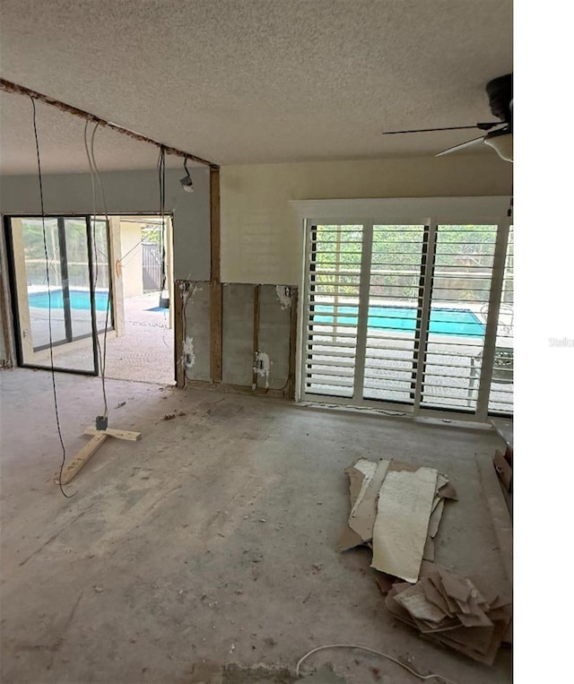 unfurnished room with ceiling fan and a textured ceiling