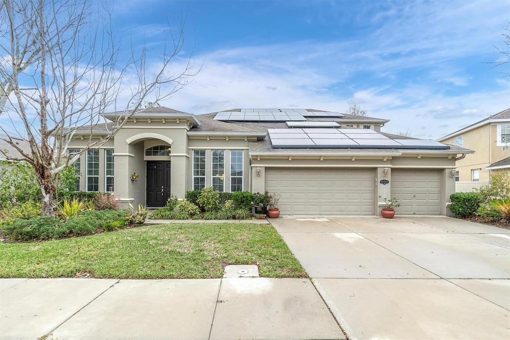 view of front facade with solar panels, a front yard, and a garage