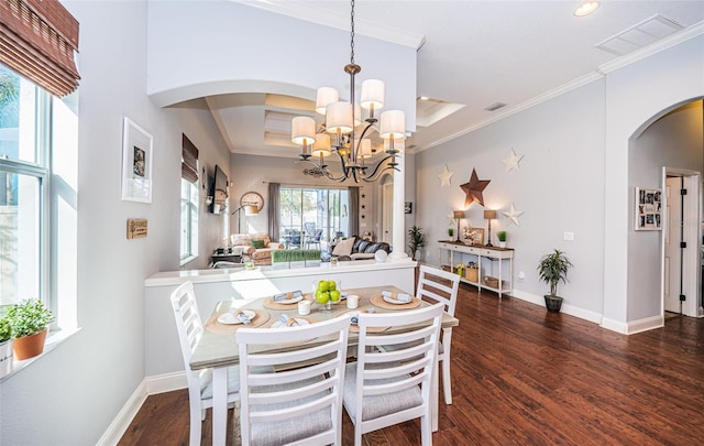 dining space featuring dark wood-type flooring, crown molding, and an inviting chandelier