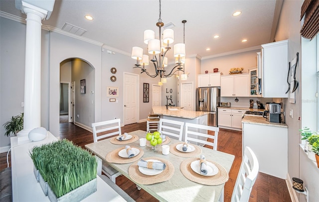 dining area with ornamental molding, dark hardwood / wood-style floors, and an inviting chandelier