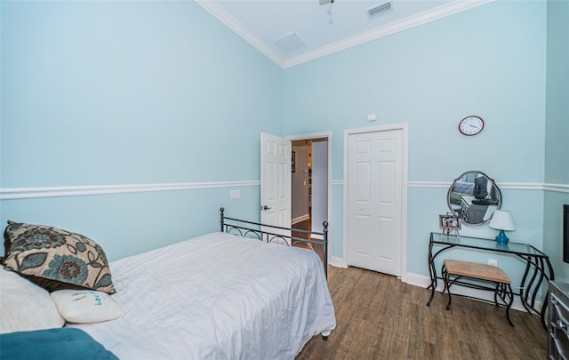 bedroom with crown molding, dark wood-type flooring, ceiling fan, and a high ceiling