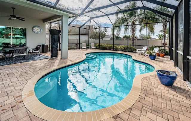 view of swimming pool with a patio, ceiling fan, and glass enclosure