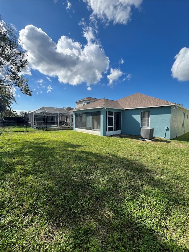 back of house with cooling unit, a sunroom, and a lawn