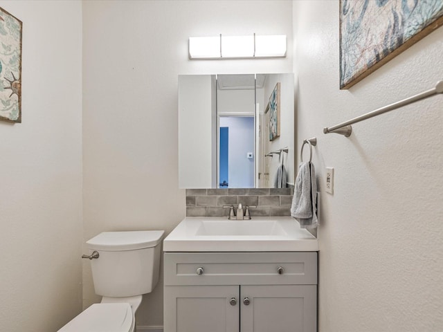 bathroom with vanity, decorative backsplash, and toilet