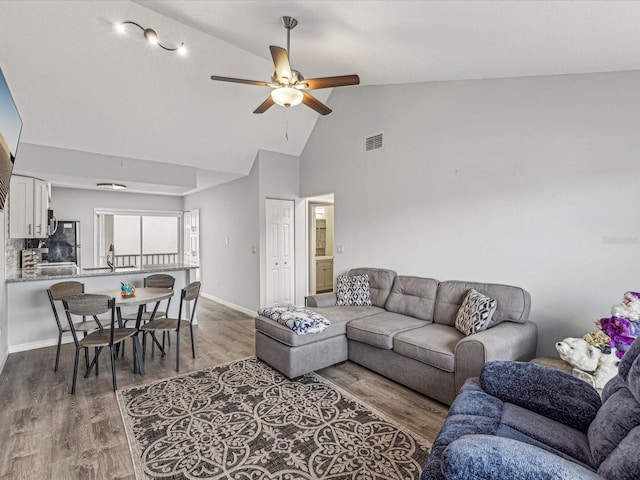 living room with wood-type flooring, high vaulted ceiling, sink, and ceiling fan