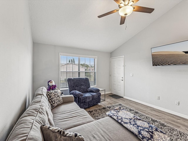 living room with hardwood / wood-style flooring, ceiling fan, and vaulted ceiling