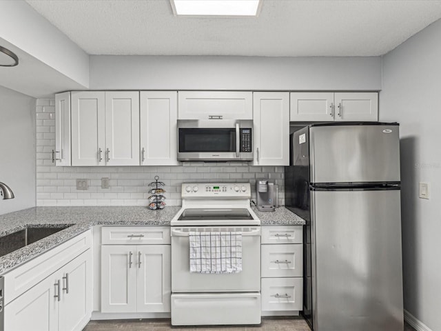 kitchen with appliances with stainless steel finishes, sink, white cabinets, and backsplash