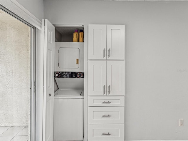 laundry room with stacked washer / drying machine and light tile patterned floors