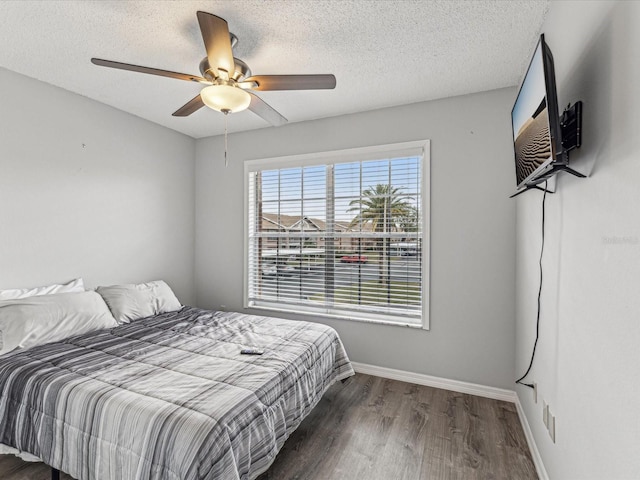 bedroom featuring dark wood-type flooring, ceiling fan, and a textured ceiling