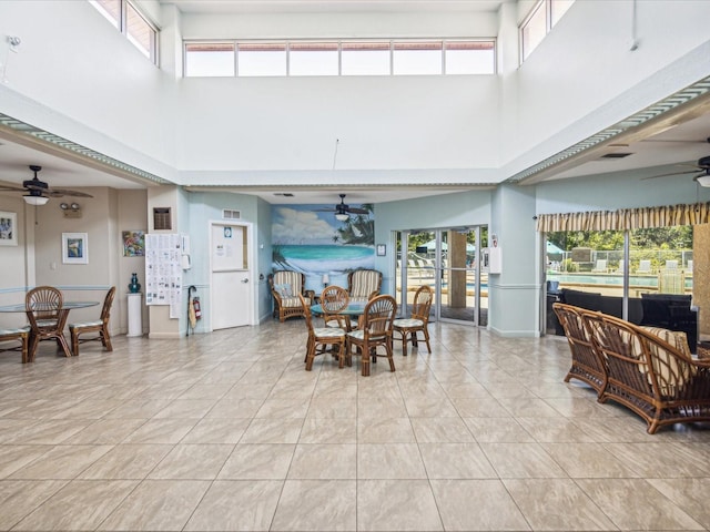 tiled dining room with ceiling fan and a high ceiling