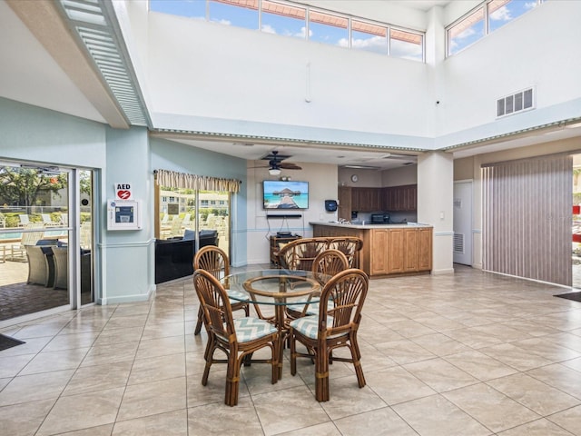 dining room featuring ceiling fan, a high ceiling, and light tile patterned floors