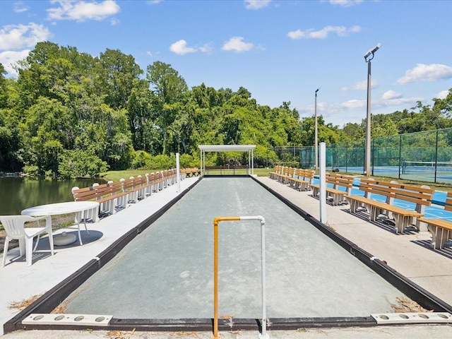 view of home's community featuring tennis court and a water view