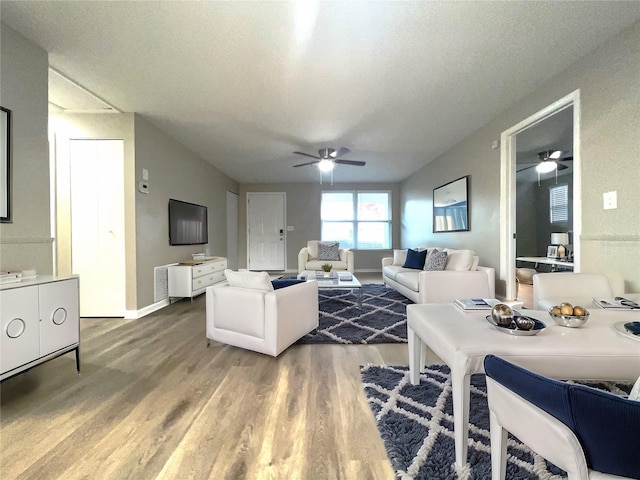 living room featuring hardwood / wood-style flooring, ceiling fan, and a textured ceiling