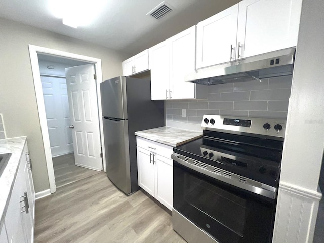 kitchen with light hardwood / wood-style floors, decorative backsplash, white cabinets, stainless steel appliances, and light stone counters