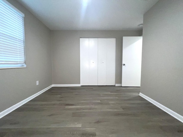 unfurnished bedroom with dark hardwood / wood-style floors and a closet