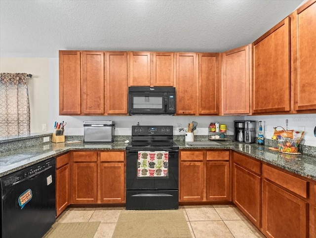 kitchen with black appliances, a textured ceiling, light tile patterned floors, and dark stone countertops