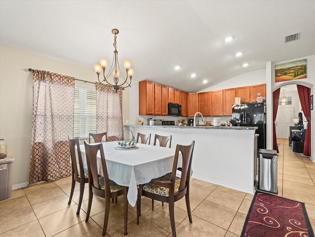 tiled dining space featuring a notable chandelier and lofted ceiling