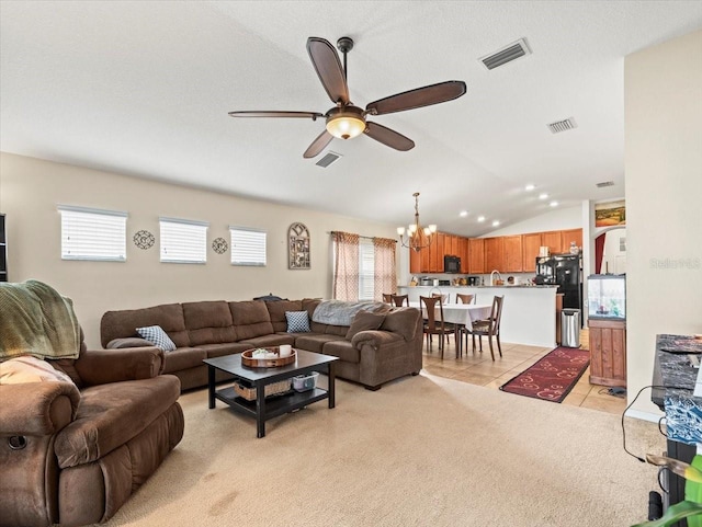 living room with ceiling fan with notable chandelier, vaulted ceiling, and light tile patterned floors