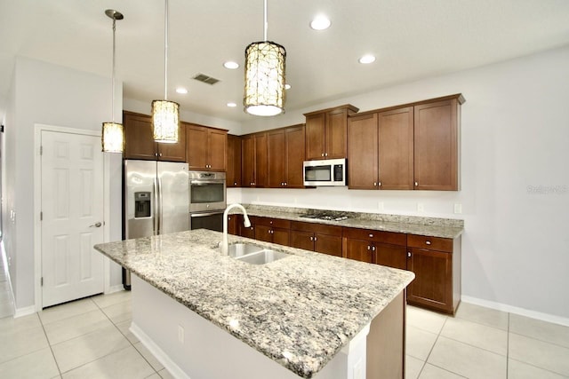 kitchen featuring sink, a center island with sink, light stone counters, and appliances with stainless steel finishes