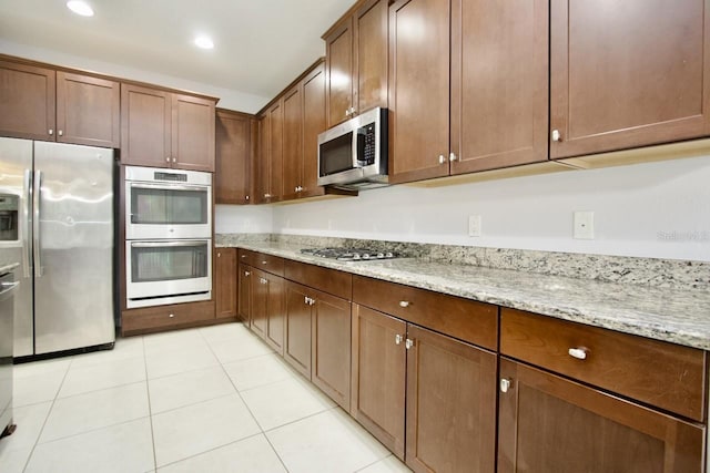 kitchen with light stone countertops, light tile patterned floors, and stainless steel appliances