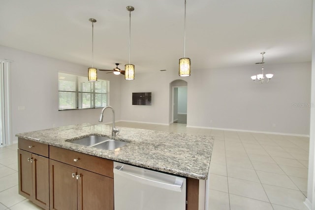 kitchen featuring stainless steel dishwasher, sink, pendant lighting, light stone counters, and a center island with sink