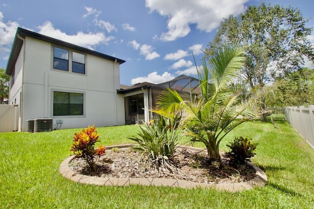 back of house with glass enclosure, a lawn, and central AC