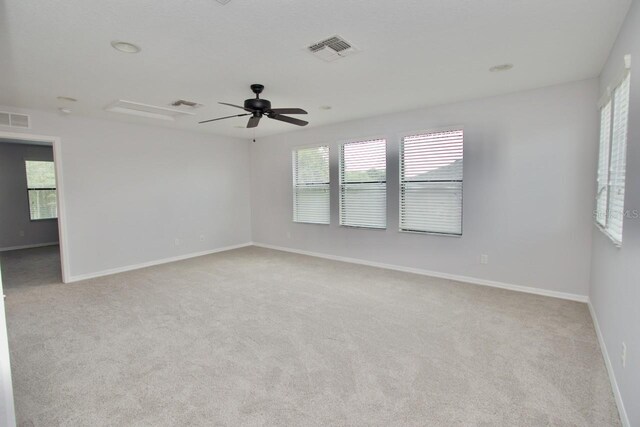 empty room with ceiling fan, light colored carpet, and plenty of natural light