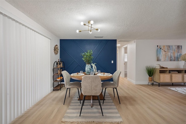 dining space with a chandelier, a textured ceiling, and wood-type flooring