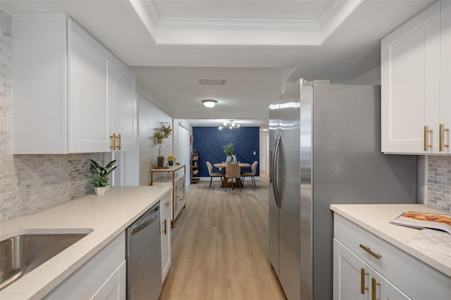 kitchen featuring light stone counters, white cabinets, a raised ceiling, and appliances with stainless steel finishes