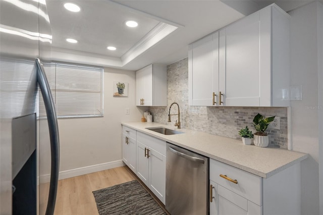 kitchen featuring light hardwood / wood-style floors, appliances with stainless steel finishes, white cabinetry, sink, and a raised ceiling